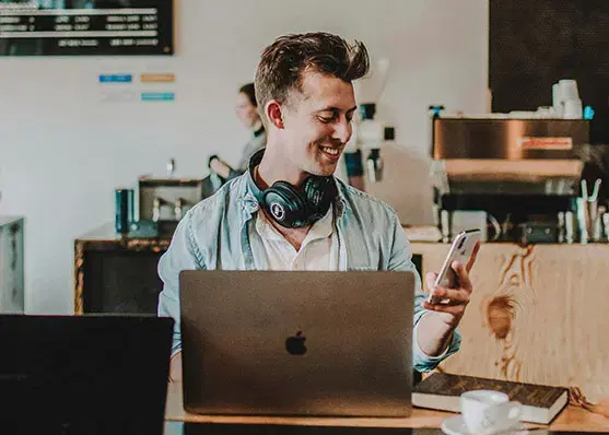 Person arbeitet lächelnd am Laptop in einem Café