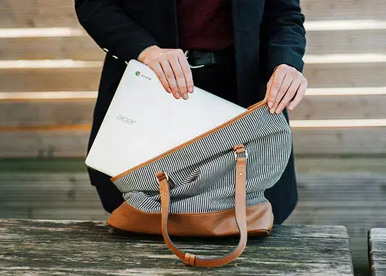 Person verstaut einen Laptop in einer Tasche