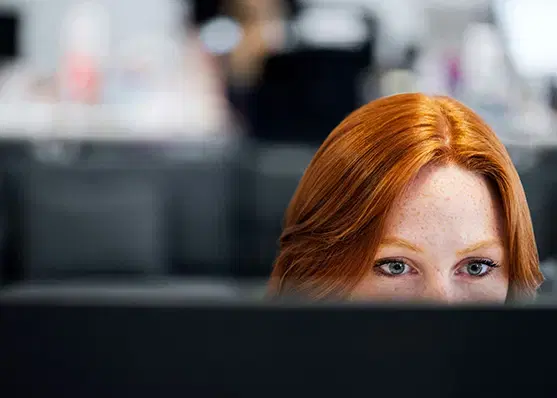 Person blickt konzentriert über einen Monitor im Büro